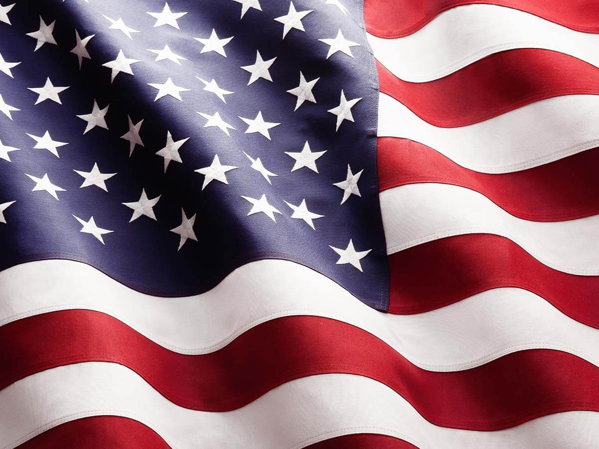 An American flag blowing in the wind atop a flagpole.